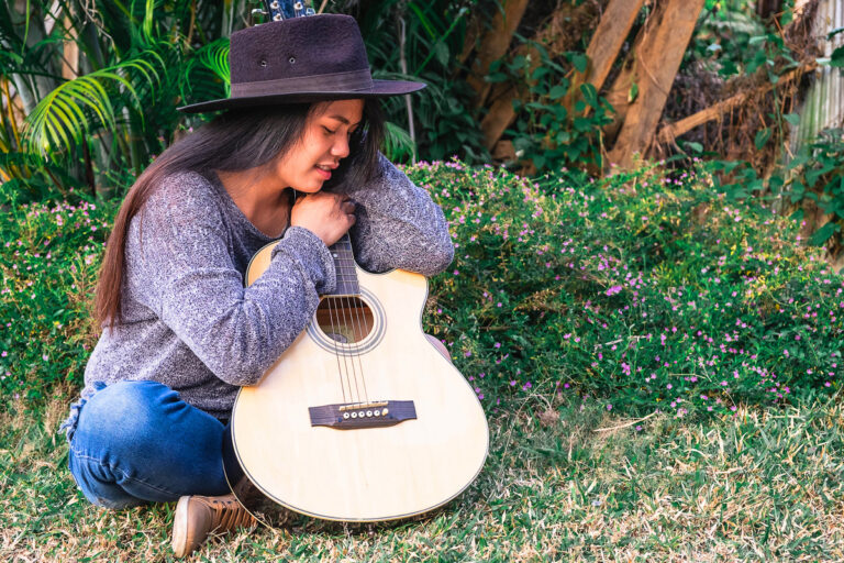 Young hipster woman playing a guitar in garden