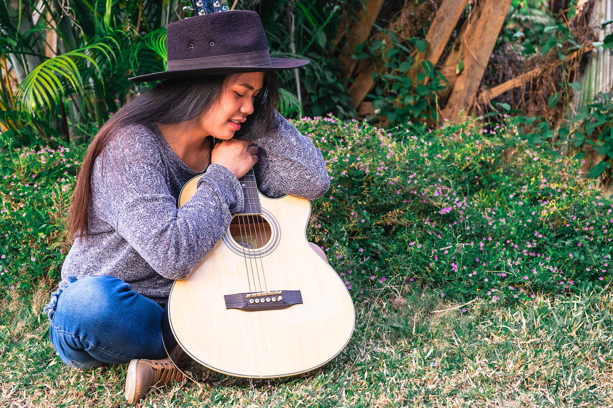 Young hipster woman playing a guitar in garden